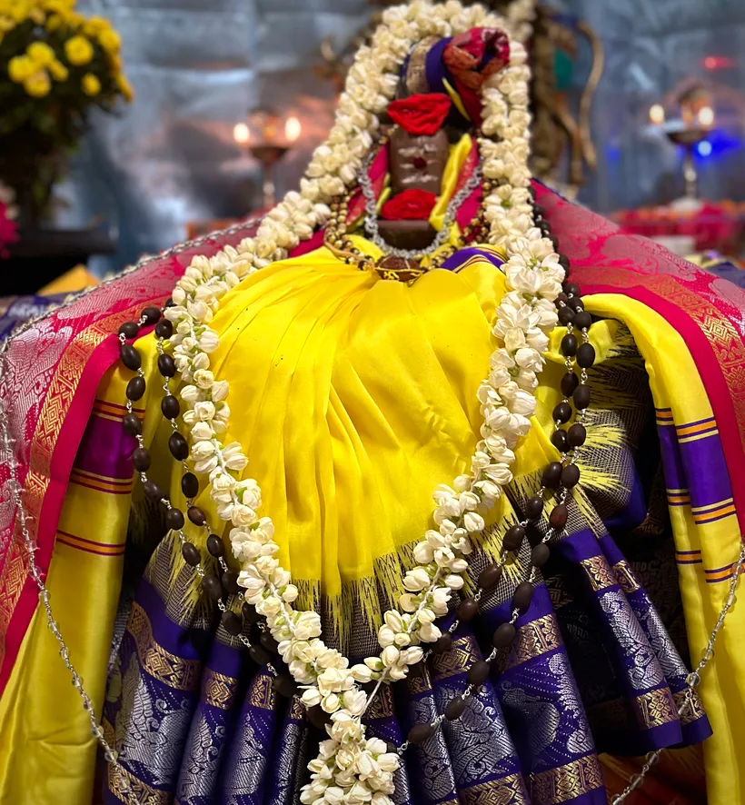 A deity adorned in silk and jasmine garlands for worship